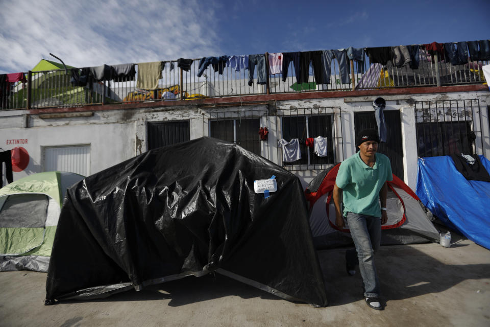 In this Dec. 2, 2018 photo, a man emerges from a tent advertising phone recharges, a service migrants have been paying 10 pesos (50 cents) for someone to watch the phone as it charges, at the former concert venue Barretal now serving as a shelter for more than 2,000 migrants in Tijuana, Mexico. Facing the possibility of a months-long wait in Tijuana before even having an opportunity to request asylum in the United States, members of the migrant caravans that have arrived in Tijuana are looking for work. Some are creating their own informal businesses. (AP Photo/Rebecca Blackwell)