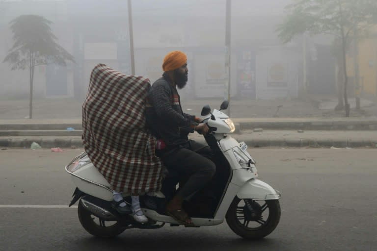 Indian schoolgirls covered in a sheet in an effort to protect themselves from heavy smog