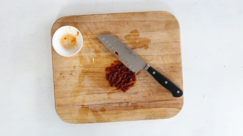 chopped chipotle pepper on cutting board with knife