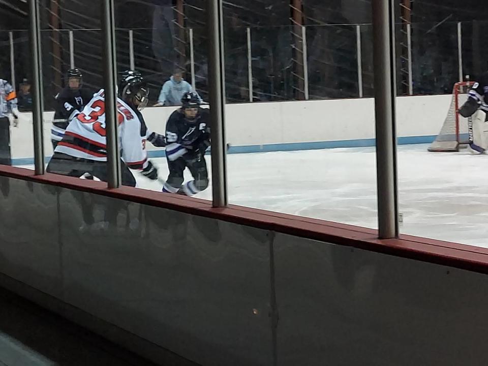 Highland’s Abe Hawkins digs the puck out along the boards against Collinsville’s Glennon Bennett during a Mississippi Valley Club Hockey Association game Thursday, Dec. 2, at Granite City Ice Rink. The Kahoks ultimately defeated the Bulldogs 7-2.