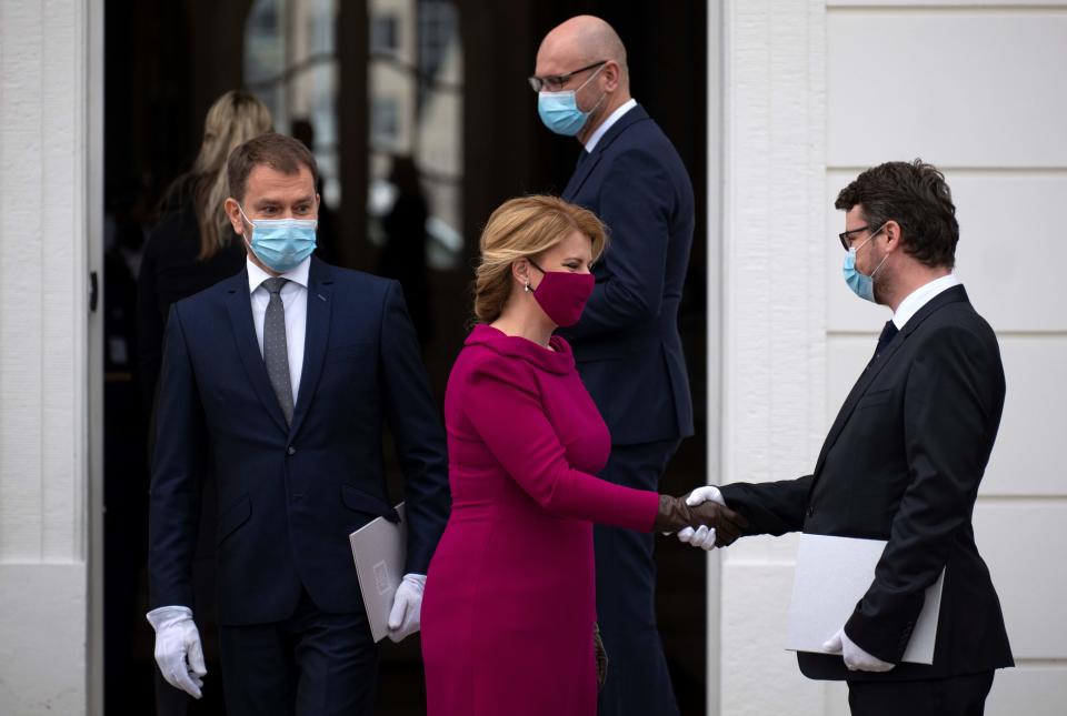 Newly appointed Slovak Prime Minister Igor Matovic (L), leader of the OLaNO anti-graft party watches President Zuzana Caputova greeting a Minister after a swearing in ceremony of the new four-party coalition government and before a family picture on March 21, 2020 outside of the Presidential palace in Bratislava. - The ceremony was held without members of the press and all appointed government members wore gloves and face mask to prevent the spread of novel coronavirus. (Photo by JOE KLAMAR / AFP) (Photo by JOE KLAMAR/AFP via Getty Images)