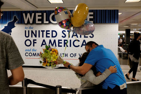 FILE PHOTO: Ahmed Khalil, an Egyptian national residing in the United States, hugs his daughters Laila, 6, and Farida, 8, as they arrive at Washington Dulles International Airport after the Trump administration's travel ban was allowed back into effect pending further judicial review, in Dulles, Virginia, U.S. on June 29, 2017. REUTERS/James Lawler Duggan/File Photo