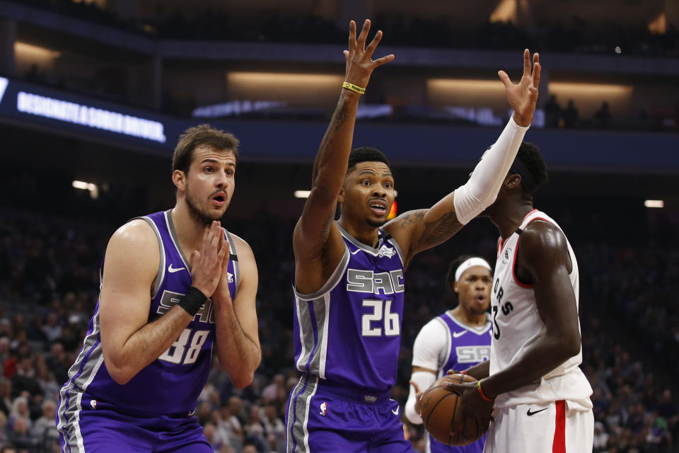 Sacramento Kings' Nemanja Bjelica, left, and Kent Bazemore, center, react after Bazemore was called for fouling Toronto Raptors forward Pascal Siakam, right, during the first quarter of an NBA basketball game in Sacramento, Calif., Sunday, March 8, 2020. (AP Photo/Rich Pedroncelli)