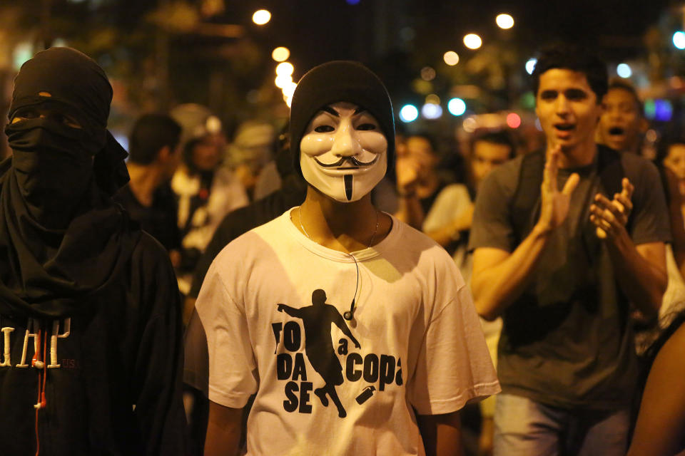 Masked demonstrators protest against the World Cup 2014, in Rio de Janeiro, Brazil, Thursday, March 27, 2014. The demonstrators call for better schools, health care, questioning the billions spent to host this year's World Cup and the 2016 Olympics. (AP Photo/Leo Correa)