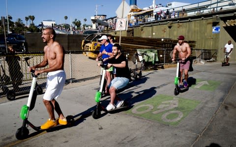 People ride Lime and Bird scooters along the strand in Santa Monica, California - Credit: Richard Vogel/AP