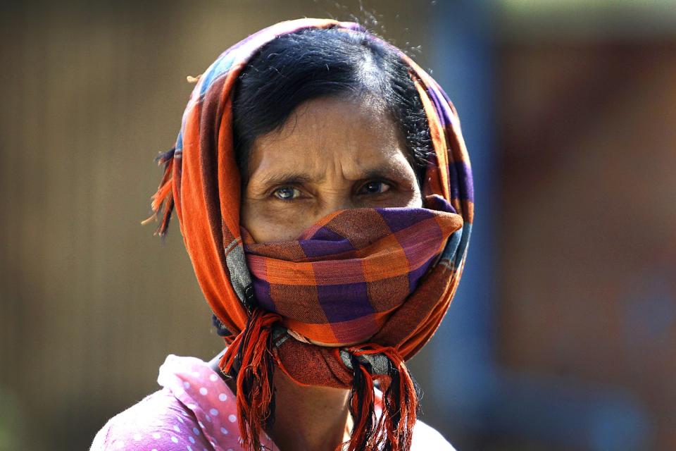 CAMBODIA: A woman dons a scarf as she watches social workers spray disinfectant to help curb the spread of the coronavirus in the slum neighborhood of Stung Meanchey in southern Phnom Penh.