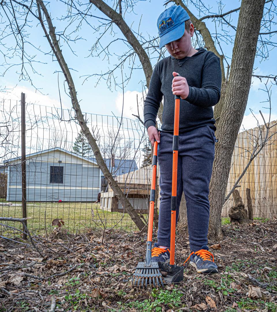 Sam Bliss, 11, cleans the backyard of dog waste in Charlotte Saturday, March 2, 2024. Sam has a method of cleaning the area in rows so he doesn't miss anything.