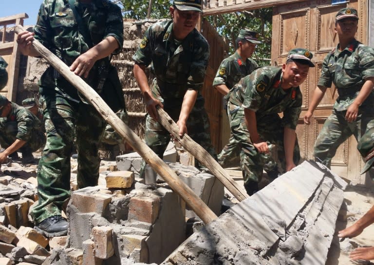 Rescuers help villagers dismantle damaged walls after an earthquake hit in Hetian, northeast China's Xinjiang region on July 3, 2015