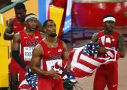 Tyson Gay of the U.S. (2ndR) and his teammates Mike Rodgers (2ndL), Trayvon Bromell (R) and Justlin Gatlin (L) fold up their national flags after learning of their disqualification in the men's 4 x 100 metres relay final during the 15th IAAF Championships at the National Stadium in Beijing, China August 29, 2015. REUTERS/David Gray