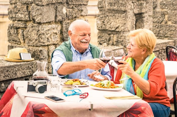 Senior couple dining outdoors, clinking wine glasses