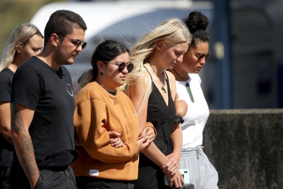 People are seen grieving and comforting each other outside the Te Manuka Tutahi Marae