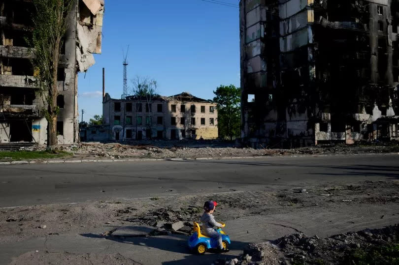 A boy plays in front of houses ruined by shelling in Borodyanka, Ukraine