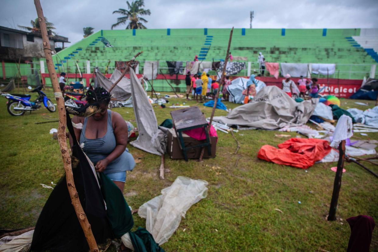 A woman works on a shelter after being hit by Tropical Storm Grace at an improvised refugee camp at Parc Lande de Gabion stadium after a 7.2-magnitude earthquake struck Haiti on Aug. 17, 2021, in Les Cayes, Haiti.