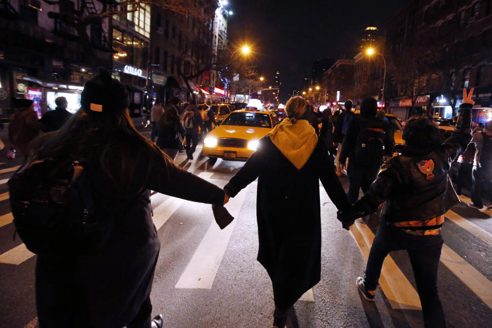 Protesters rallying against a grand jury's decision not to indict the police officer involved in the death of Eric Garner hold hands as they make their way up Ninth Avenue in the early morning hours of Friday, Dec. 5, 2014, in New York. (AP Photo/Jason DeCrow)