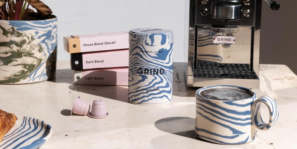 a marbled coffee jar and mug on a table next to a coffee machine and pods