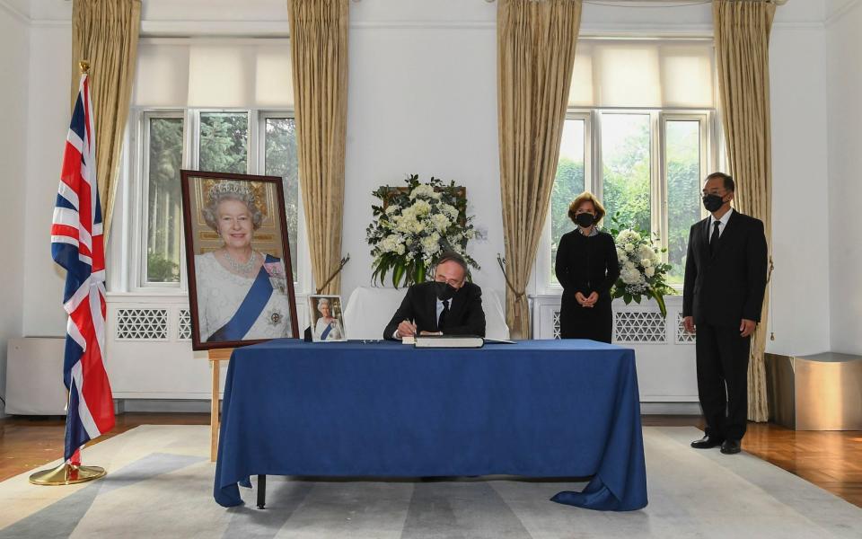 Wang Qishan signs a condolence book next to Caroline Wilson, British Ambassador to China, at the British Embassy in Beijing - Xie Huanchi/Xinhua via AP