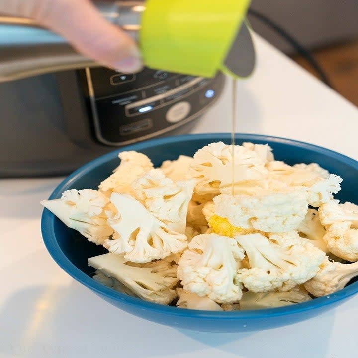 Cauliflower in a bowl drizzled with olive oil.