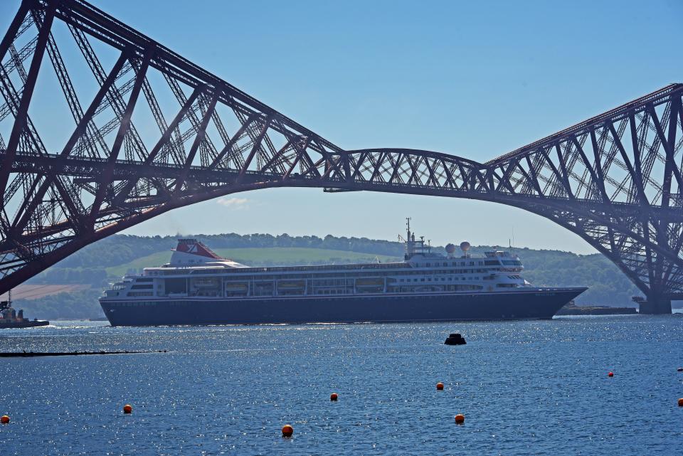 The Fred Olsen Cruise Lines ship Braemar passes under the Forth Bridge en route to Rosyth Basin where she and three sister ships will be laid up during the Covid-19 pandemic, on June 1, 2020 in Rosyth, Scotland. The four Fred Olsen ships Braemar, Balmoral, Black Watch and Boudicca have been anchored in the Firth of Forth as the cruise industry slumped as a result of the Covid-19 pandemic, but have now been moved to the Babcock facility at Rosyth where the aircraft carriers HMS Queen Elizabeth and HMS Prince of Wales were built. (Photo by Ken Jack/Getty Images)