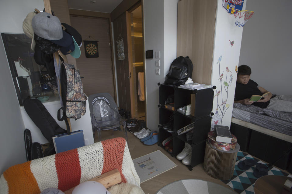 <p>Donny Chan lee sobre la cama de su apartamento de Hong Kong. La imagen es un buen reflejo del tamaño de estas viviendas. (AP Photo/Kin Cheung) </p>