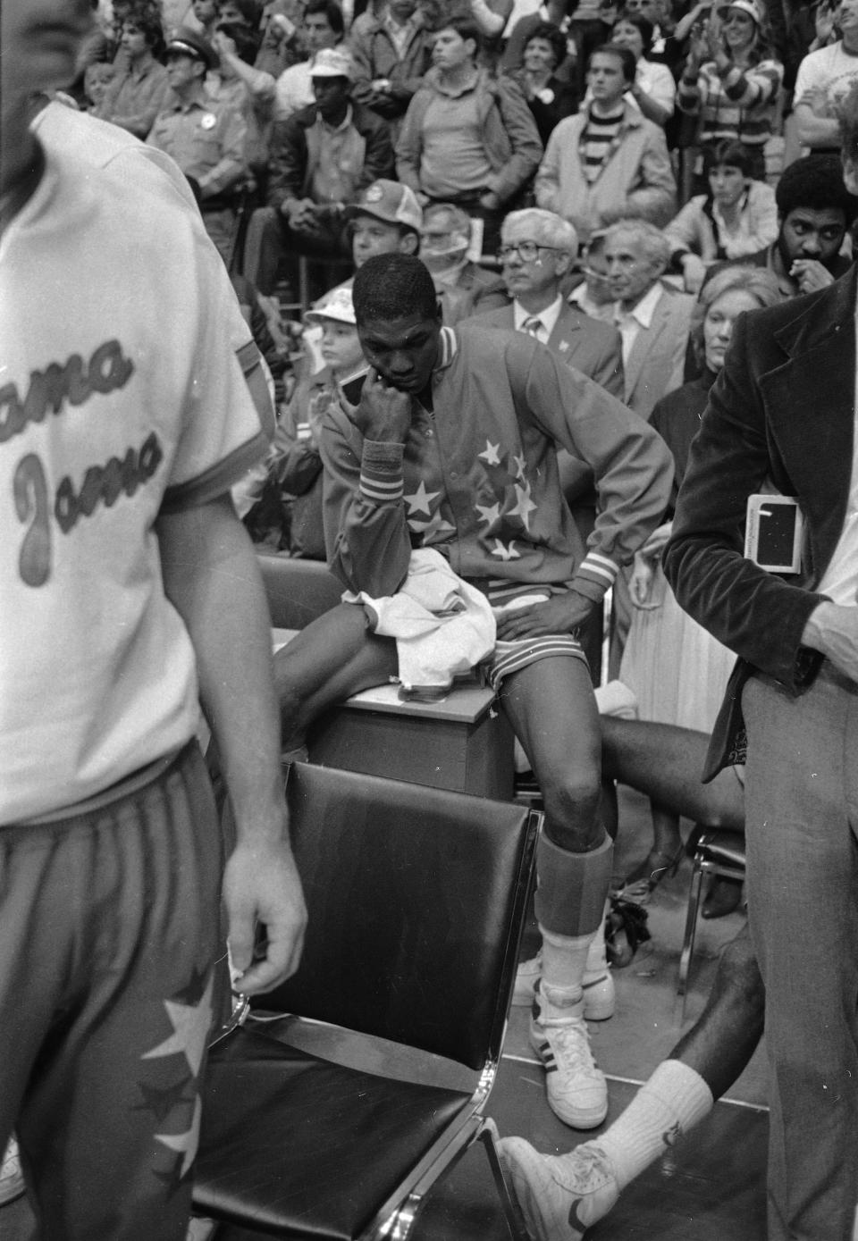 FILE - In this April 5, 1983, file photo, University of Houston's Akeem Olajuwon sits after the last second shot by Lorenzo Charles of North Carolina State won the Final Four championship game game in Albuquerque, N.M. The NCAA and networks across the sports dial have infused fans with a hoops fix by rebroadcasting epic NCAA Tournament games. Coaches and players involved in those games are adding insight and a dash of humor by live tweeting during the replay. (AP Photo/File)