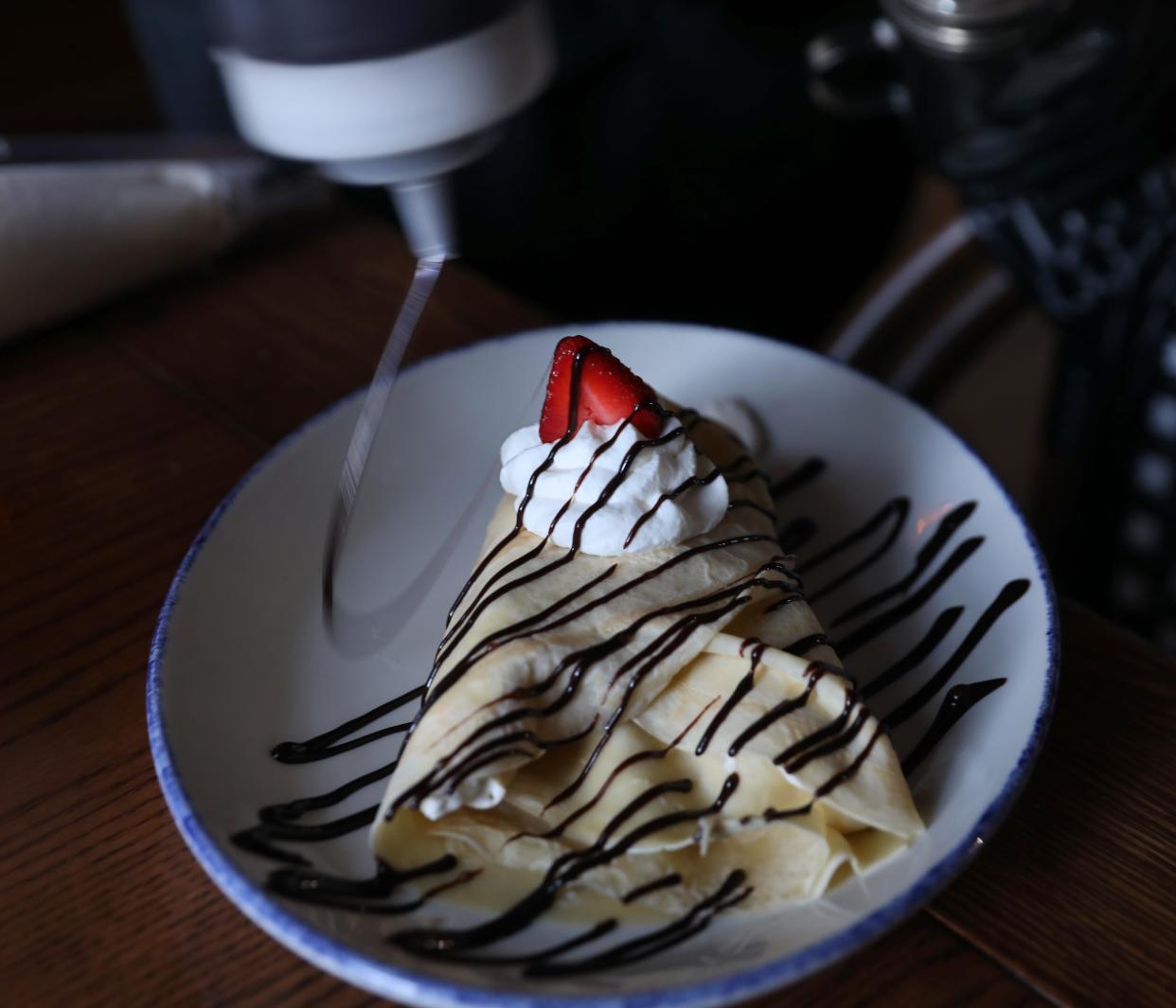 Sous-chef Eddie Durkin adds chocolate sauce as creates a Nutella Fruit Crepe at the opening of the newest Simply Crepes located in Penfield Monday, Oct. 10, 2022. 
