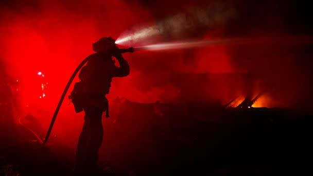 PHOTO: Fire fighter Andrew Alves hoses down hotspots in homes that were burnt as the Mill Fire burns near Weed, Calif., Sept. 2, 2022. (Fred Greaves/Reuters)