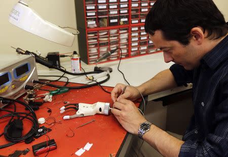 Electronic engineer Sebastian Vicario works on a prosthetic arm at the Bioparx Health Technology company in Santa Fe, north of Buenos Aires December 18, 2014. REUTERS/Enrique Marcarian