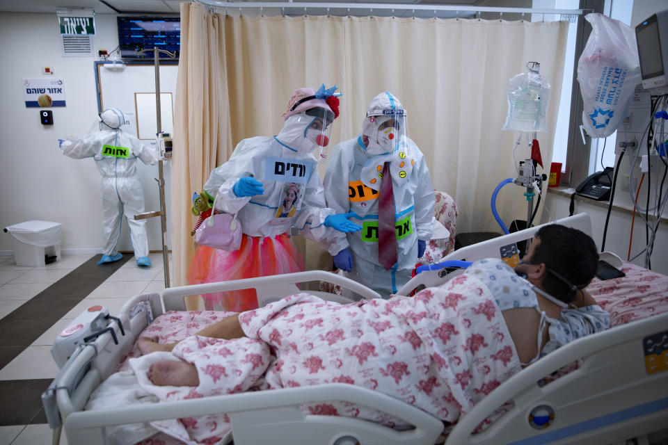 Clowns wearing protective equipment entertain a COVID-19 patient in the intensive care ward for coronavirus patients at Shaare Zedek Medical Center in Jerusalem, Monday, Nov. 23, 2020. (AP Photo/Oded Balilty)