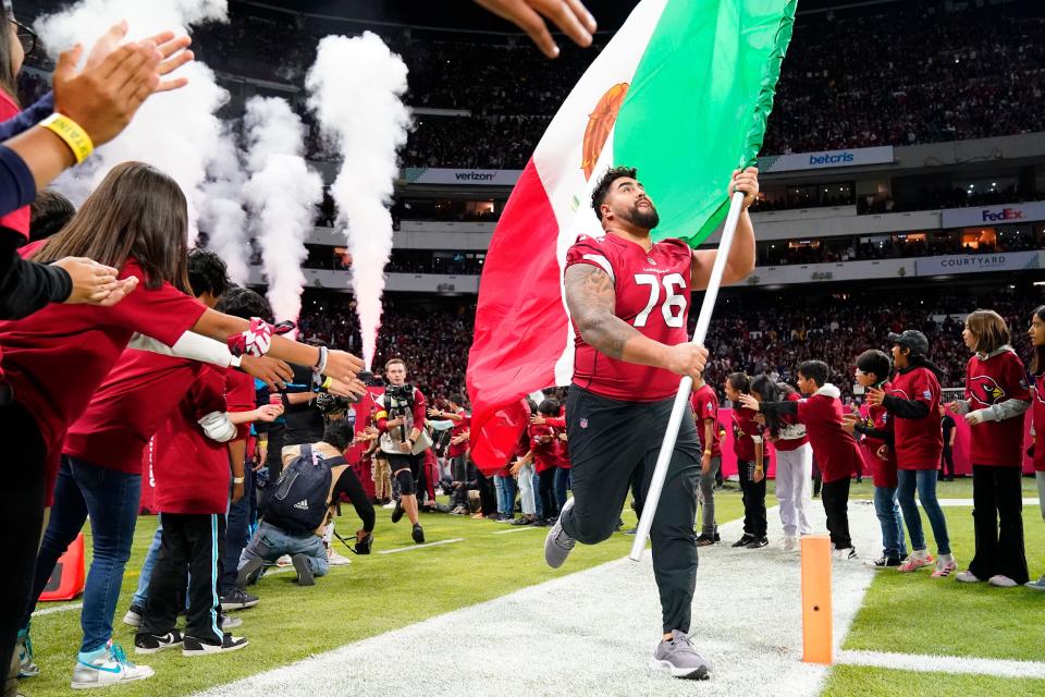 Arizona Cardinals guard Will Hernandez (76) carries the Mexican flag onto the field prior to the game against the San Francisco 49ers in the first half at Estadio Azteca in Mexico City on Nov. 21, 2022.