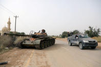 Members of Libyan internationally recognised government forces pass near a damaged tank belonging to Eastern forces in Al Hira area, south western Tripoli, Libya April 23, 2019. REUTERS/Hani Amara