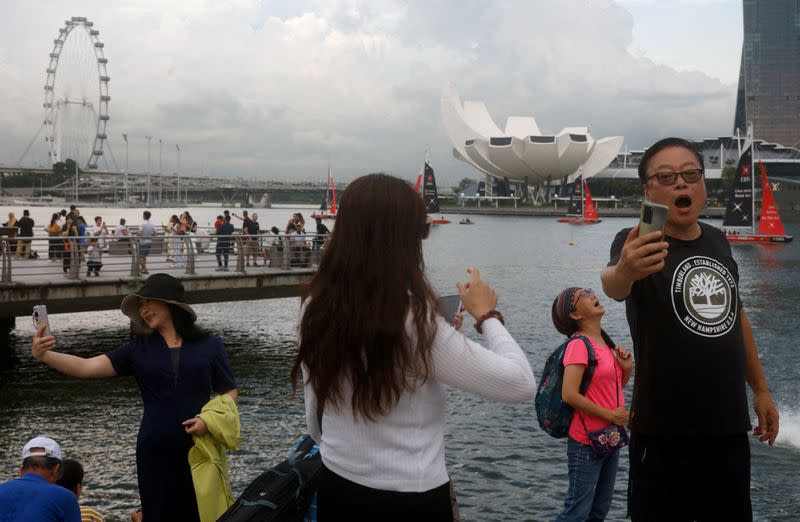 FILE PHOTO: Chinese tourists pose for photos with the Merlion statue at Marina Bay in Singapore