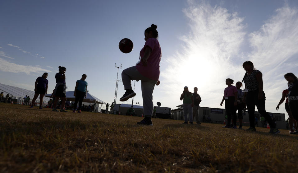 FILE - In this July 9, 2019, file photo, immigrants play soccer at the U.S. government's newest holding center for migrant children in Carrizo Springs, Texas. A federal volunteer at the Biden administration's largest shelter for unaccompanied immigrant children says paramedics were called regularly during her the two weeks she worked there. She said panic attacks would occur often after some of the children were taken away to be reunited with their families, dashing the hopes of those left behind. (AP Photo/Eric Gay, File)