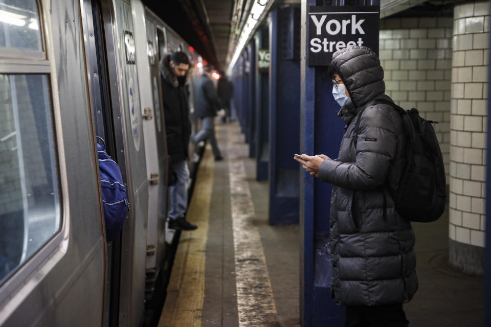 A subway customer wearing a face mask waits to board a car in the Brooklyn borough of New York, Monday, March 16, 2020. New York leaders took a series of unprecedented steps Sunday to slow the spread of the coronavirus, including canceling schools and extinguishing most nightlife in New York City. According to the World Health Organization, most people recover in about two to six weeks, depending on the severity of the illness. (AP Photo/John Minchillo)