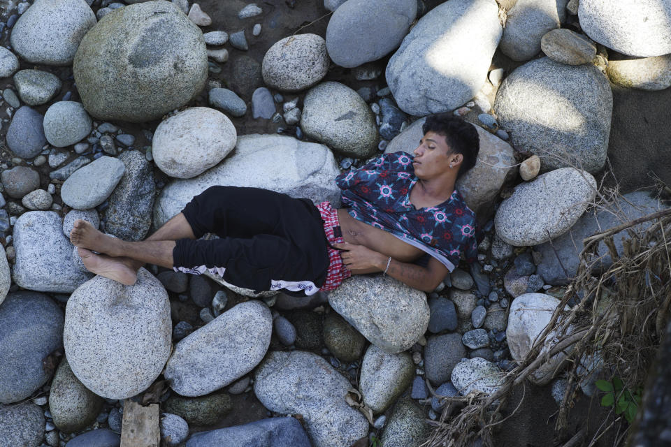 A man who is part of a migrant caravan, sleeps on a bed of rocks on the banks of the in Huixtla River, Chiapas state, Mexico, Tuesday, Oct. 26, 2021, on a day of rest before continuing their trek across southern Mexico to the U.S. border. (AP Photo/Marco Ugarte)