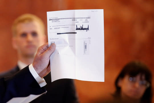 <p>Republican presidential candidate Donald Trump holds up a check while addressing the media about donations to veterans foundations at Trump Tower in New York City, May 31, 2016. (Reuters/Lucas Jackson) </p>