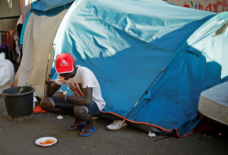 A migrant eats at a makeshift camp in Via Cupa (Gloomy Street) in downtown Rome, Italy, August 1, 2016. REUTERS/Max Rossi