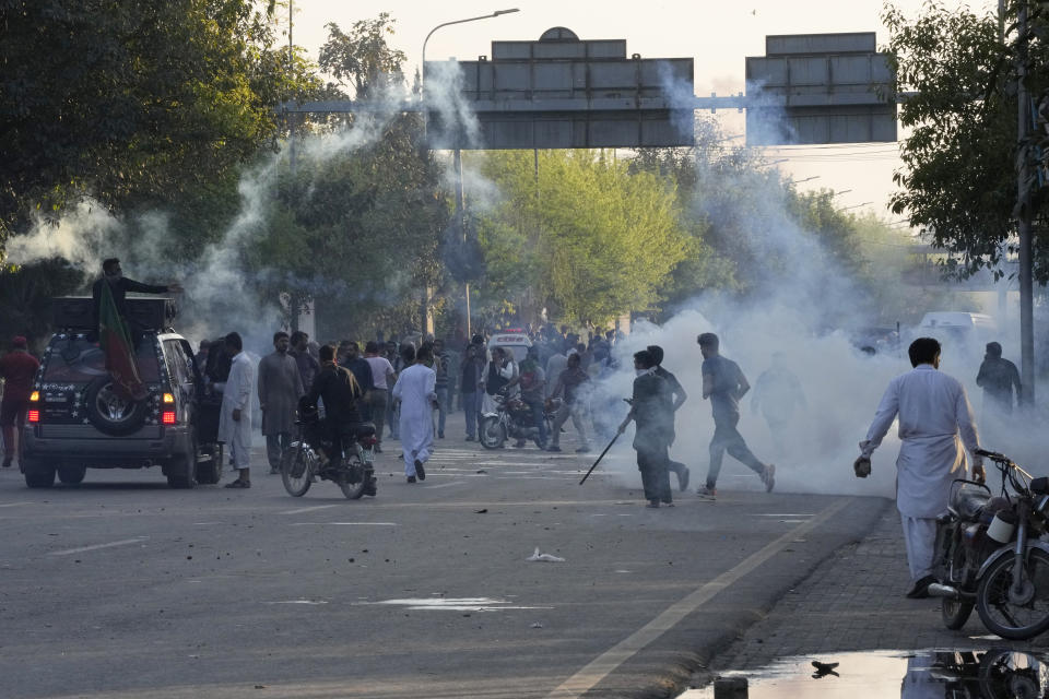 Supporters of Pakistan's former Prime Minister Imran Khan run for cover as police fire tear gas shells to disperse them during clashes, in Lahore, Pakistan, Wednesday, March 8, 2023. Pakistani police used water cannons and fired tear gas to disperse supporters of the country's former Prime Minister Khan Wednesday in the eastern city of Lahore. Two dozen Khan supporters were arrested for defying a government ban on holding rallies, police said. (AP Photo/K.M. Chaudary)