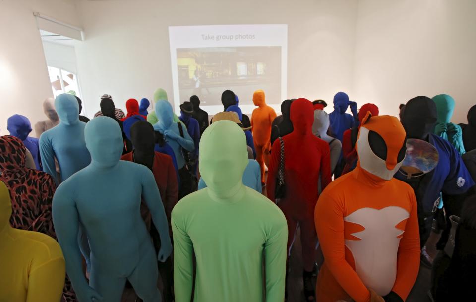 Participants wearing Zentai costumes listen to a briefing before a march down the shopping district of Orchard Road during Zentai Art Festival in Singapore