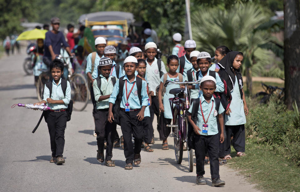 In this Thursday, Aug. 9, 2018 photo, school children walk on a road in Mayong, 45 kilometers (28 miles) east Gauhati, India. A draft list of citizens in Assam, released in July, put nearly 4 million people on edge to prove their Indian nationality. Nativist anger churns through Assam, just across the border from Bangladesh, with many believing the state is overrun with illegal migrants. (AP Photo/Anupam Nath)