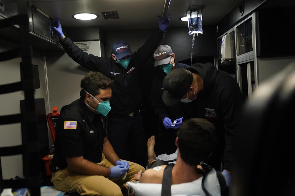 Emergency medical workers Trenton Amaro, from left, Joshua Hammond, Thomas Hoang and Charles Navarro are crammed in an ambulance as they treat a patient in Placentia, Calif., Friday, Jan. 8, 2021. EMTs and paramedics have always dealt with life and death — they make split-second decisions about patient care, which hospital to race to, the best and fastest way to save someone — and now they're just a breath away from becoming the patient themselves.(AP Photo/Jae C. Hong)