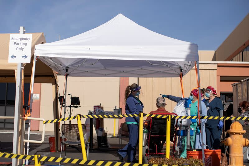 Healthcare workers attend to a patient as St. Mary Medical Center resorts to using triage tents outside in California