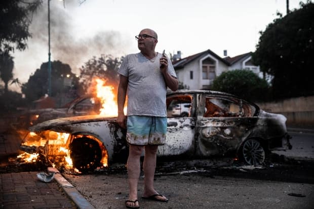 Jacob Simona stands by his burning car, destroyed during clashes between Israeli Arabs and police in the city of Lod last Tuesday.