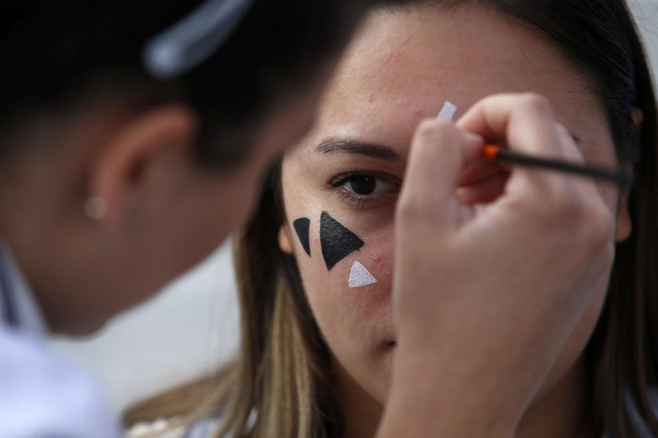 In this photo taken Sept. 25, 2019, members of a rights group paint a face with makeup to confuse the Huawei surveillance video cameras with face-recognition software in Belgrade, Serbia. With public authorities disclosing little about how the cameras work, the group has set up a tent to ask pedestrians whether they know they are being watched. (AP Photo/Darko Vojinovic)