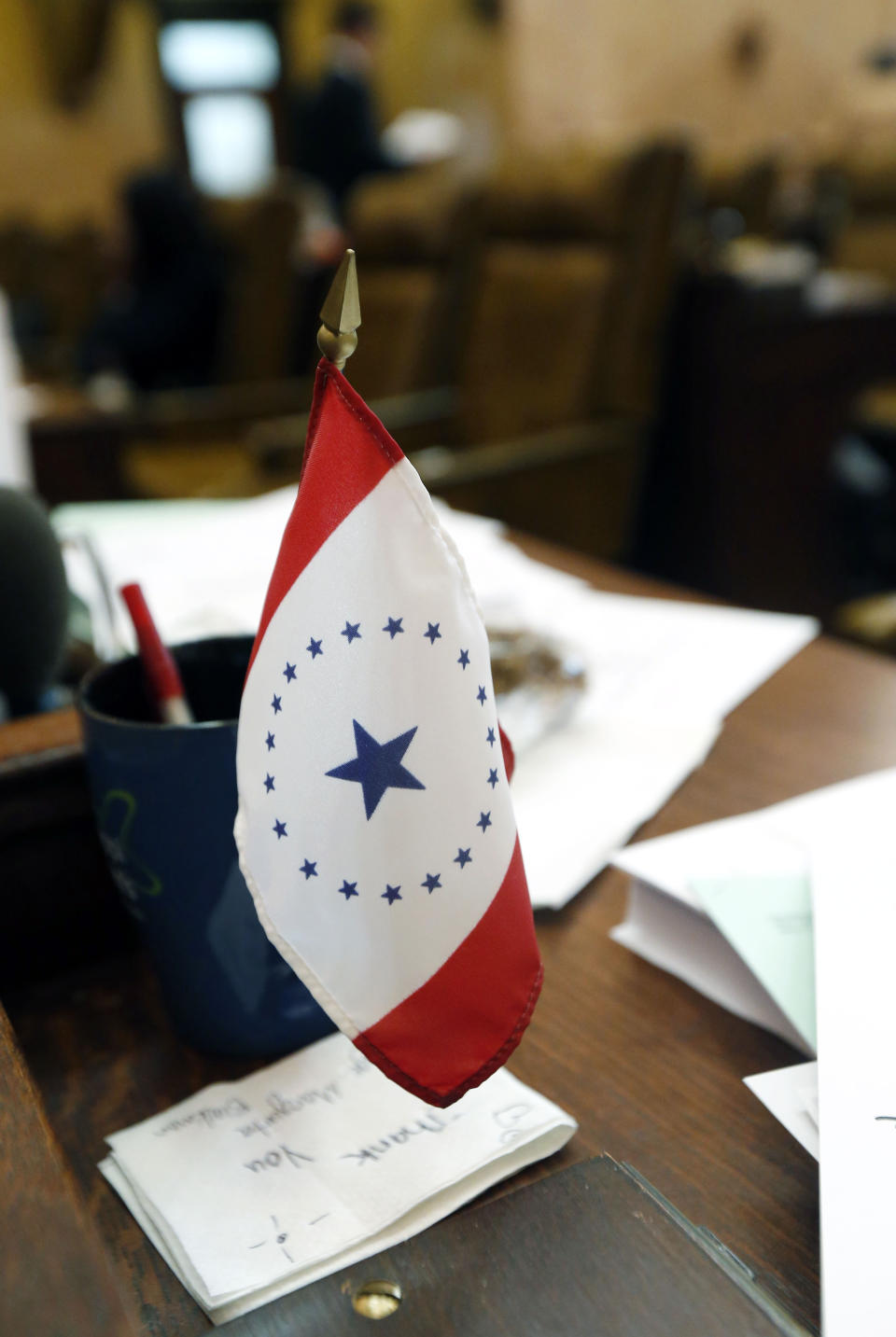 FILE- In this Feb. 17, 2016 file photo, a new conceptualized Mississippi state flag sits on the desk of Rep. Kathy Sykes, D-Jackson, at the Capitol in Jackson, Miss. The flag was designed by Laurin Stennis, the granddaughter of the late U.S. Sen. John Stennis, D-Miss. Mississippi residents who want a state flag without the Confederate battle emblem now have an alternative at least for their license plates. Gov. Phil Bryant on Tuesday, April 17, 2019, signed a bill authorizing designs for several new specialty license plates (AP Photo/Rogelio V. Solis, File)