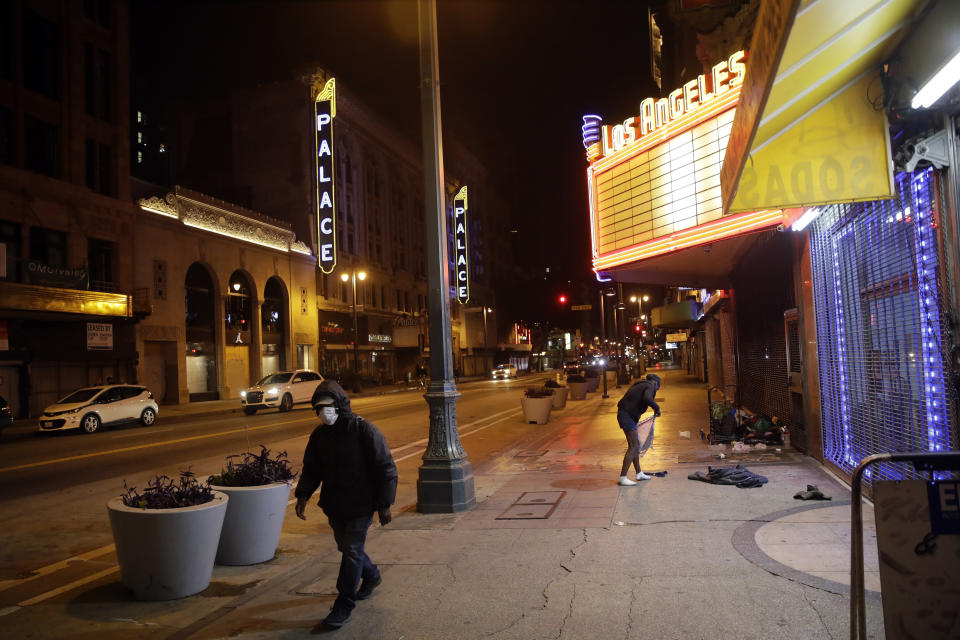 A masked pedestrian walks along Broadway Avenue on Wednesday, April 1, 2020, in Los Angeles. Los Angeles Mayor Eric Garcetti has recommended that the city's 4 million people wear masks when going outside amid the spreading coronavirus. (AP Photo/Marcio Jose Sanchez)