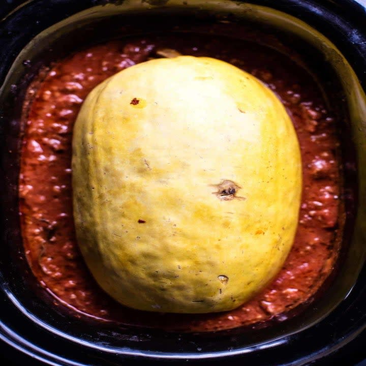 A spaghetti squash with Bolognese sauce in a slow cooker.