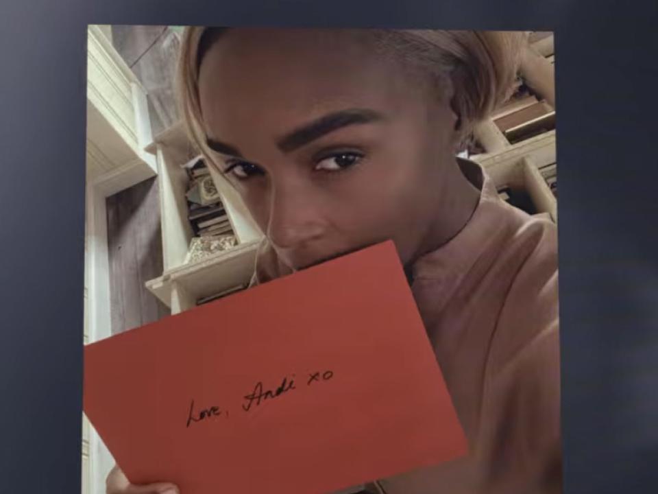 Janelle Monae as Andi holding a red envelope.