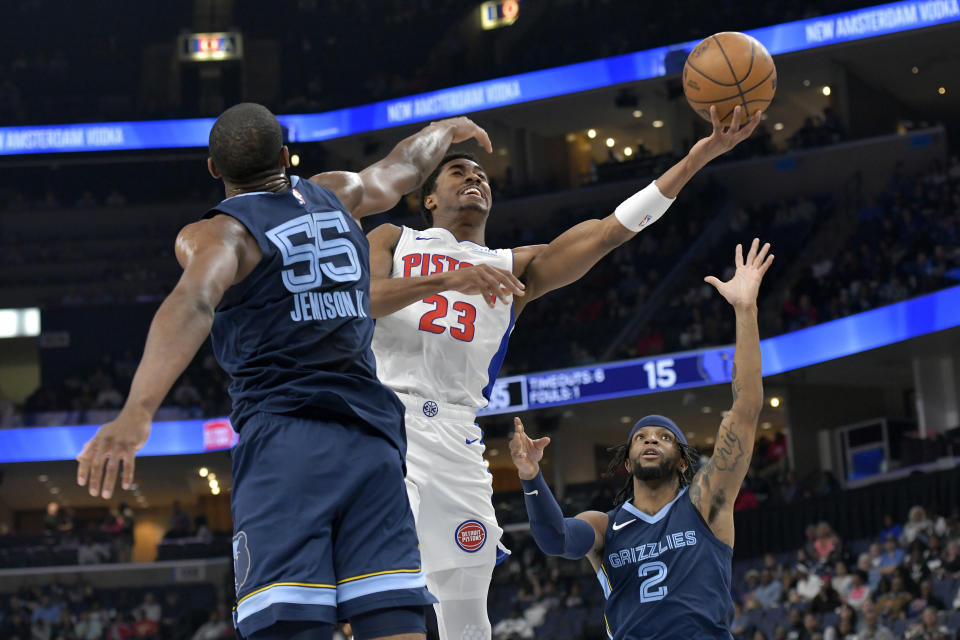 Detroit Pistons guard Jaden Ivey (23) shoots between Memphis Grizzlies center Trey Jemison (55) and guard Zavier Simpson (2) in the first half of an NBA basketball game Friday, April 5, 2024, in Memphis, Tenn. (AP Photo/Brandon Dill)