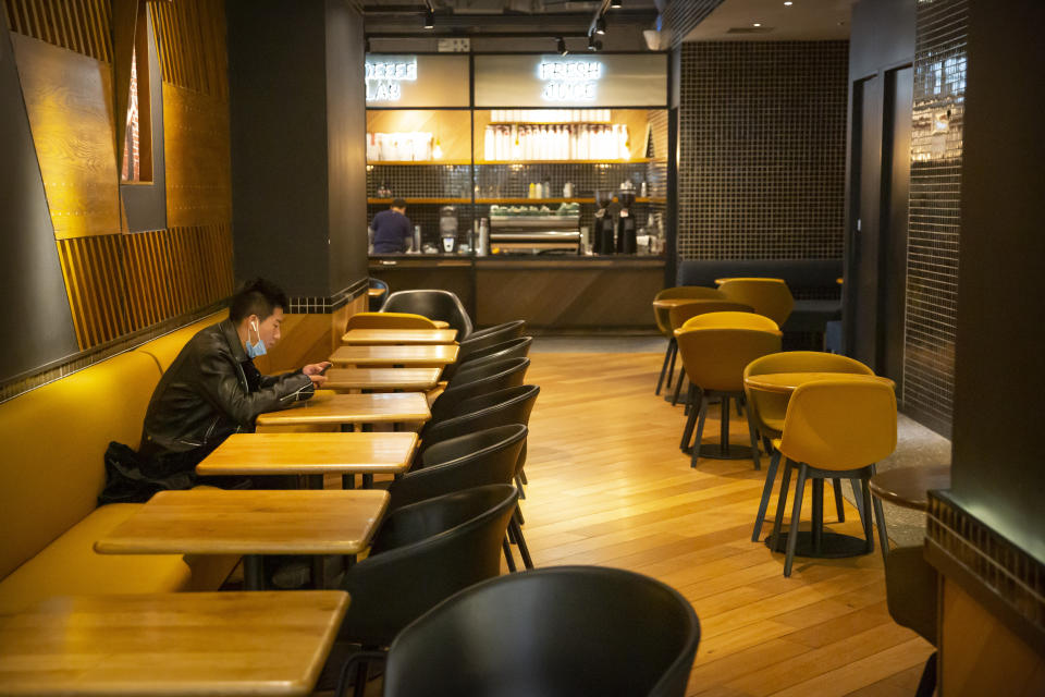 In this Tuesday, Jan. 28, 2020 photo, a man wearing a face mask waits for his food at an empty restaurant in Beijing. Fears of a virus outbreak have kept many indoors and at home in China's capital. Cultural landmarks such as the Great Wall and Forbidden City have closed their doors to visitors, nearly deserted shopping malls have reduced their operating hours, and restaurants that remain open draw just a handful of customers. (AP Photo/Mark Schiefelbein)