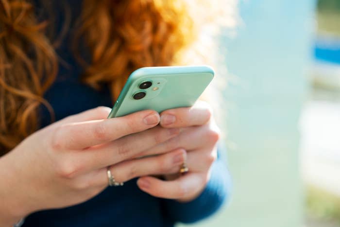 Person holding a smartphone with both hands, likely texting or browsing